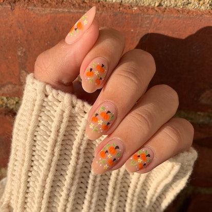 Tiny pumpkins with flowers are a cute pumpkin nail art design idea for fall 2023.