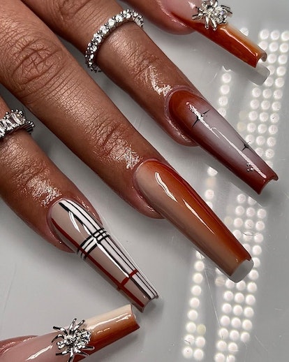 A Burberry-inspired plaid nail art design mixed with orange gradient nails.