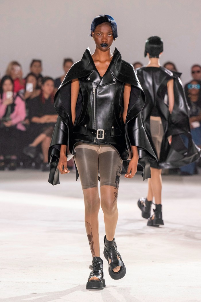 A model in a leather jacket which features a cape over the shoulders