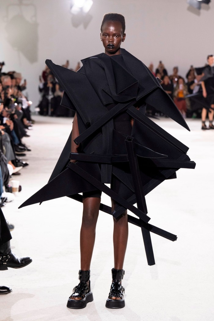 A model in a black dress made up of sculptural shapes