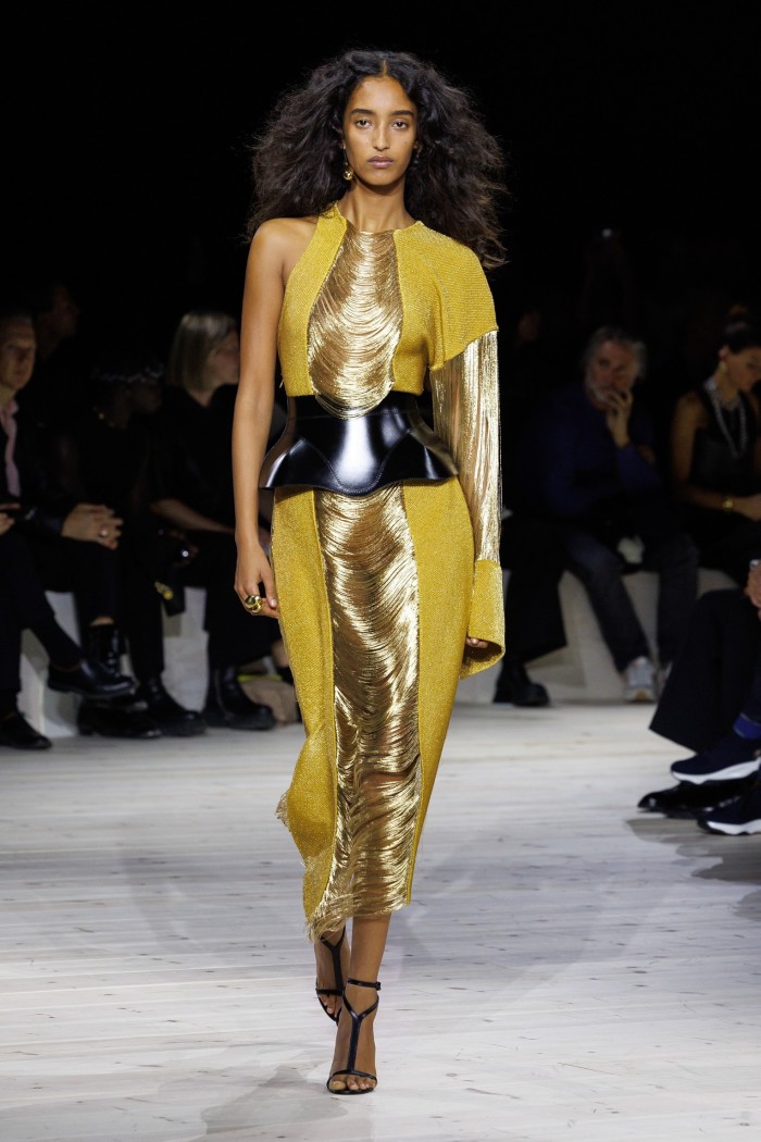 A model on a catwalk on a gold and yellow dress