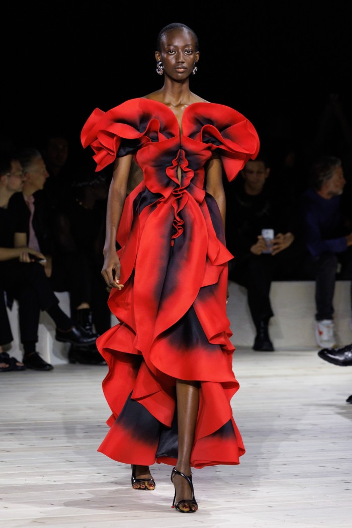 A model on a catwalk in a ruffled red gown