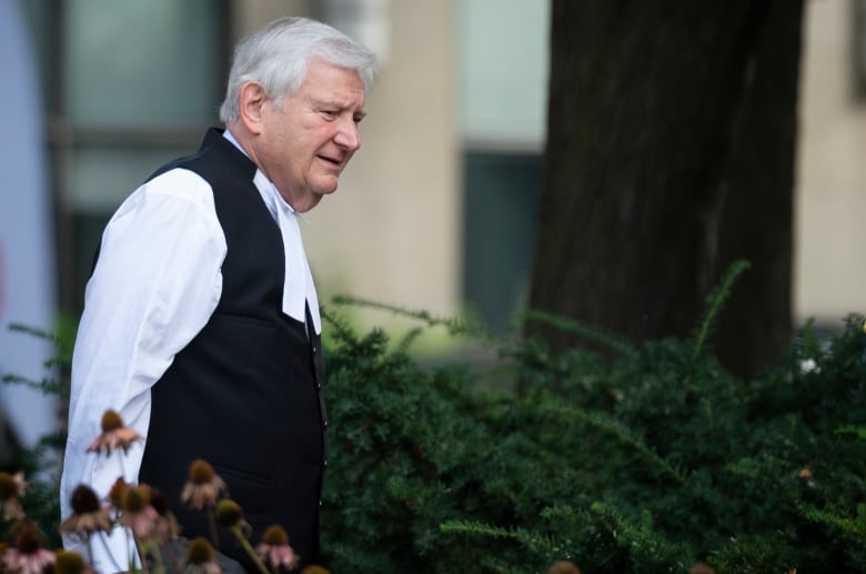 A man in formal court clothing walks outside.