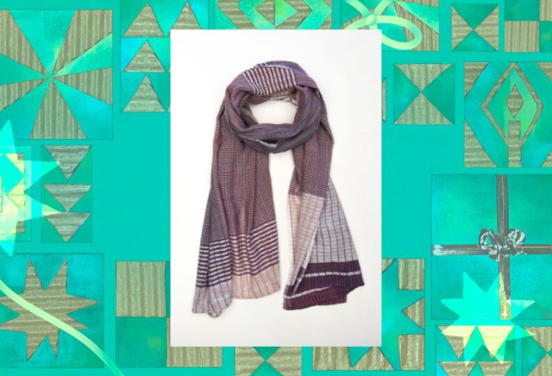 A hand-woven scarf that features a variety of designs, there's a part that's plaid, another part that's striped, in muted gray, brown and cream colors. The image is set against a decorative green background accented with stars, gift boxes and strands of ribbon.