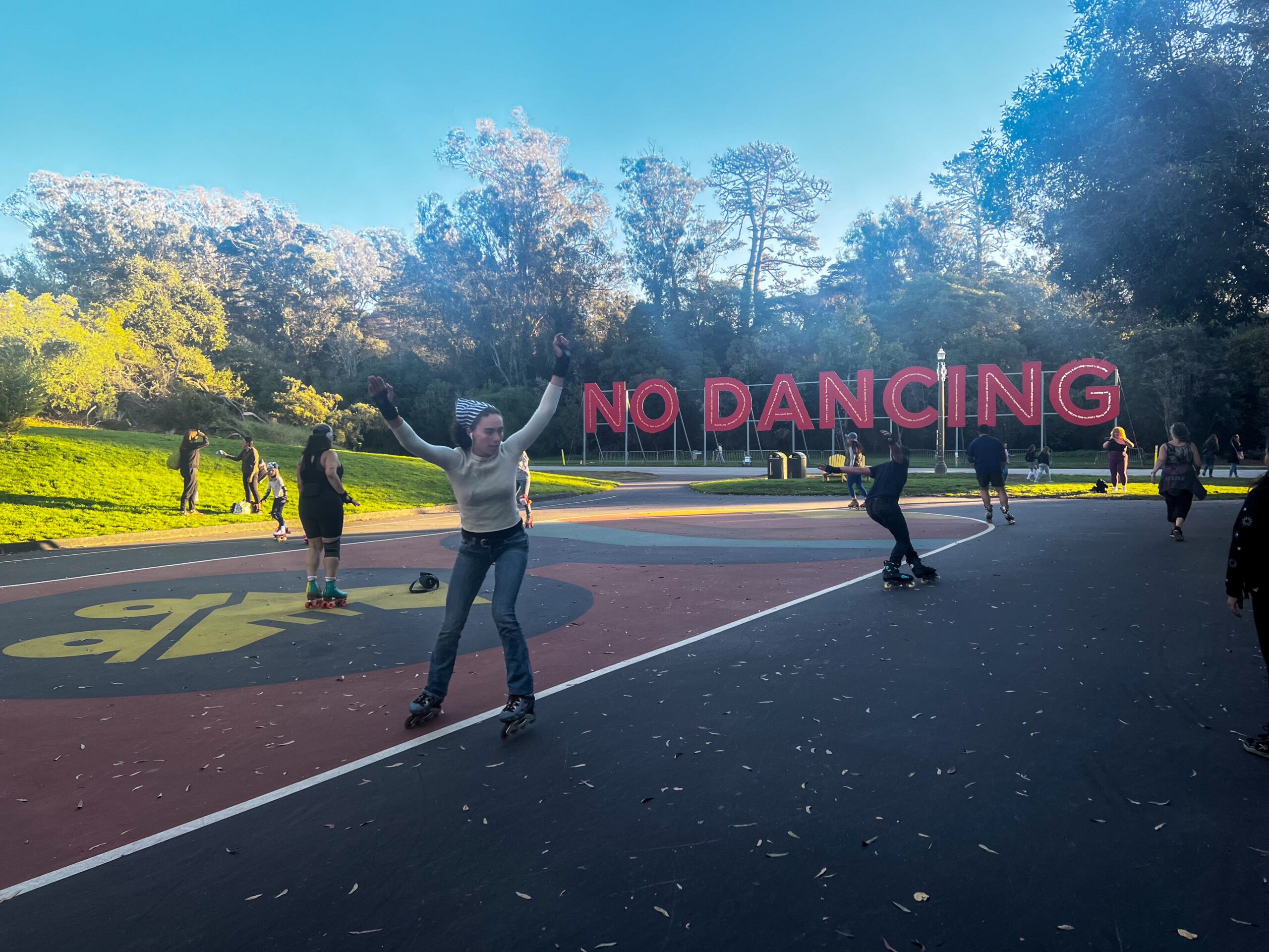 People roller skate with a big red sign that reads "No Dancing"