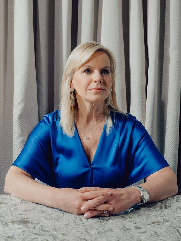 Gretchen Carlson is sitting for a portrait with her hands clasped on a countertop.