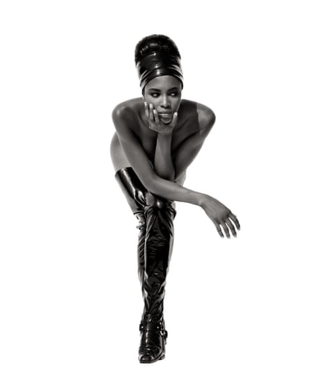 Model Naomi Campbell wearing black thigh-high leather boots and matching hair wrap, against white background, May 1990,