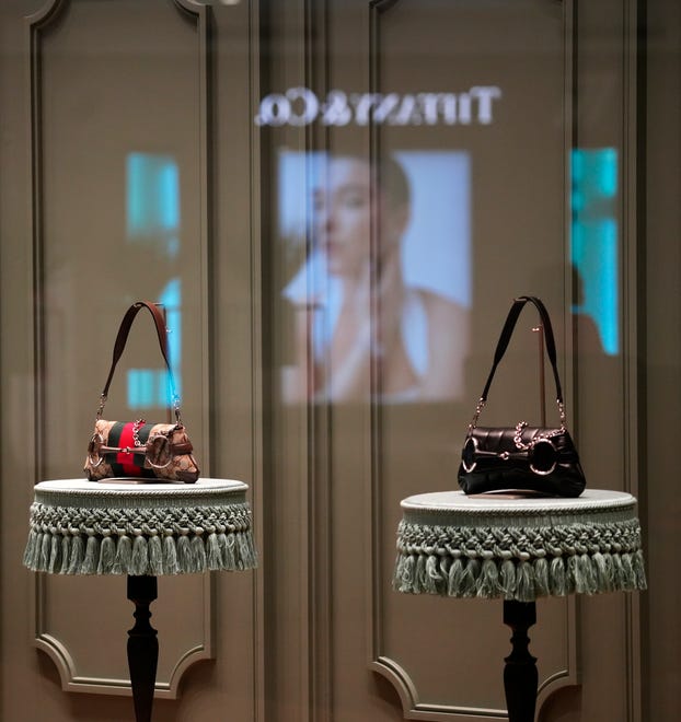 Purses on display at Gucci in Kenwood Towne Centre, Wednesday, Oct. 26, 2023. Tiffany & Co. is reflected in the glass. This is Gucci’s first location in Cincinnati. They opened in December of 2022, across from Louis Vuitton, near Nordstrom.