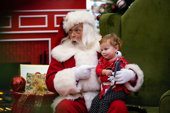 Charlotte, almost 2-years-old, right, sits on Santa’s lap for a photo on Friday, Nov. 17, 2023, at Kenwood Towne Centre in Kenwood, Ohio.