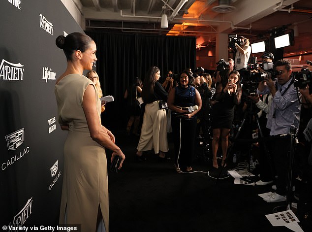 Meghan smiles for the assembled press in Los Angeles yesterday evening