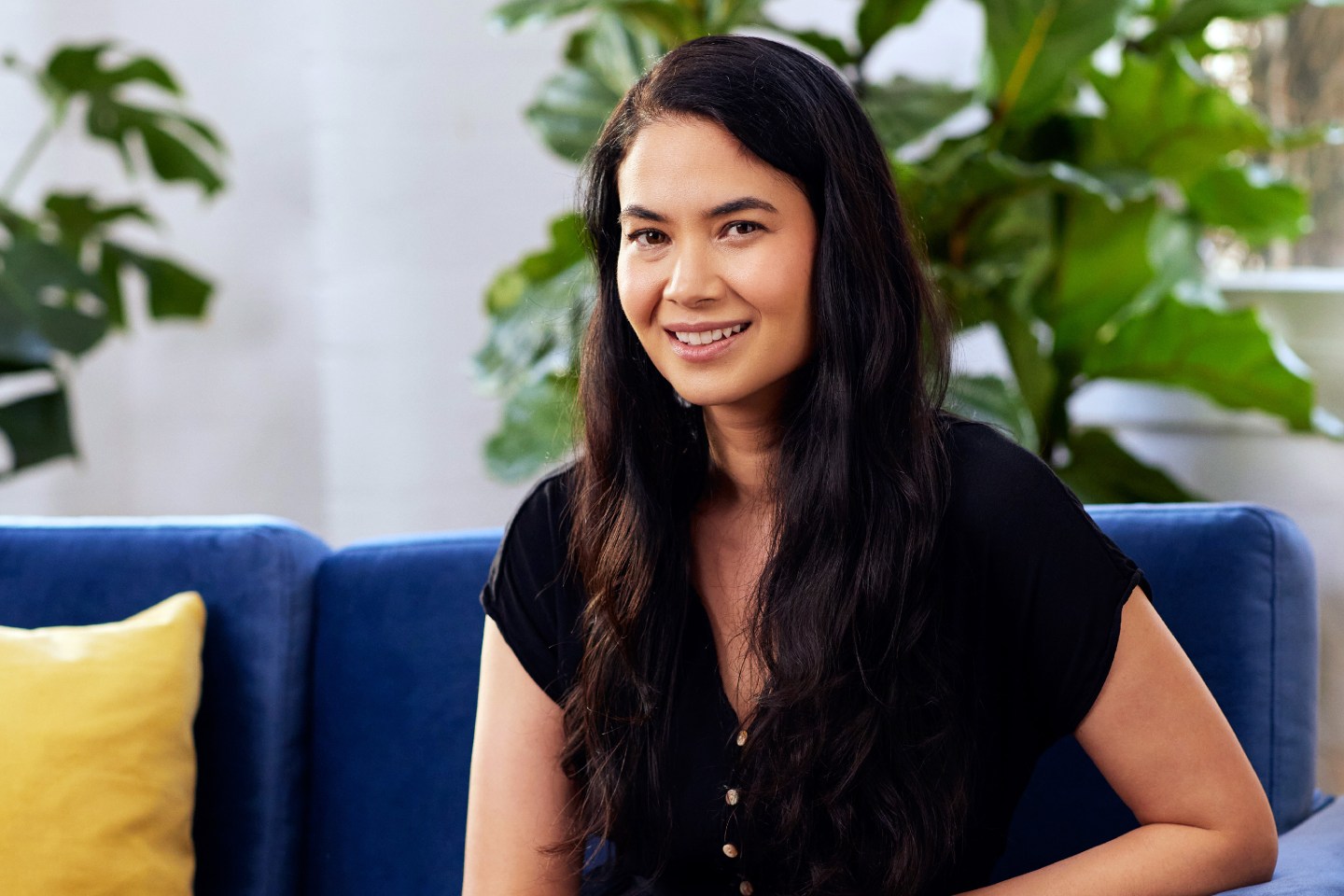 Portrait of Canva CEO Melanie Perkins sitting on couch.