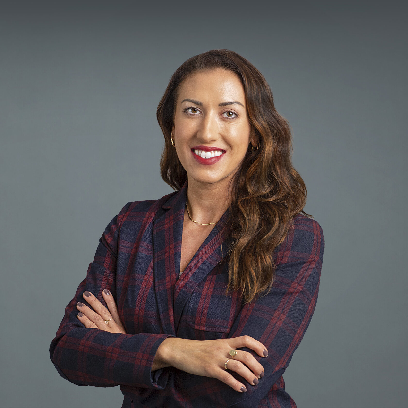 a woman wearing plaid with wavy brown hair smiling at the camera