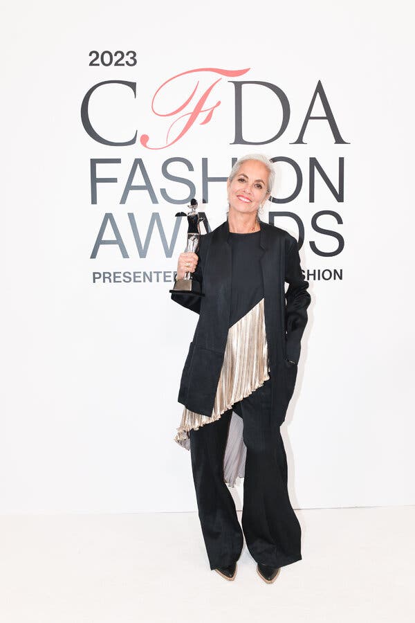 Ms. Cornejo poses, standing before a CFDA printed backdrop with s statuette in her hand.