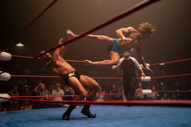 A wrestler flies through the air, cicking another wrestler in a ring