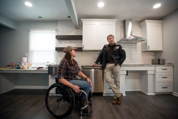 Laurie Wood in her renovated kitchen Tuesday morning, Nov. 21,2023 with Tom Jennings with Tidewater Pro Build. Wood has been in a wheelchair for the past 11 years due to a training accident while a member of the Norfolk Sheriff's Office. She has lived in her Virginia Beach home for the past 20 years and since her accident some of her home has been inaccessible to her. Tidewater Pro Build of Suffolk has renovated the home of the Navy veteran for free to make the entire home wheelchair accessible. (Bill Tiernan/ For The Virginian-Pilot)