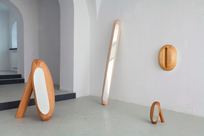 oddly shaped curved wooden mirrors in a gallery space