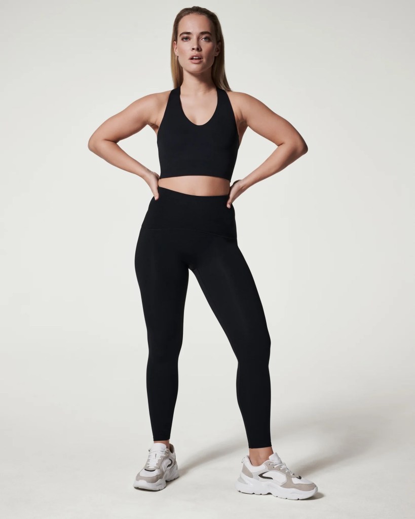 A model in a black sports bra and leggings