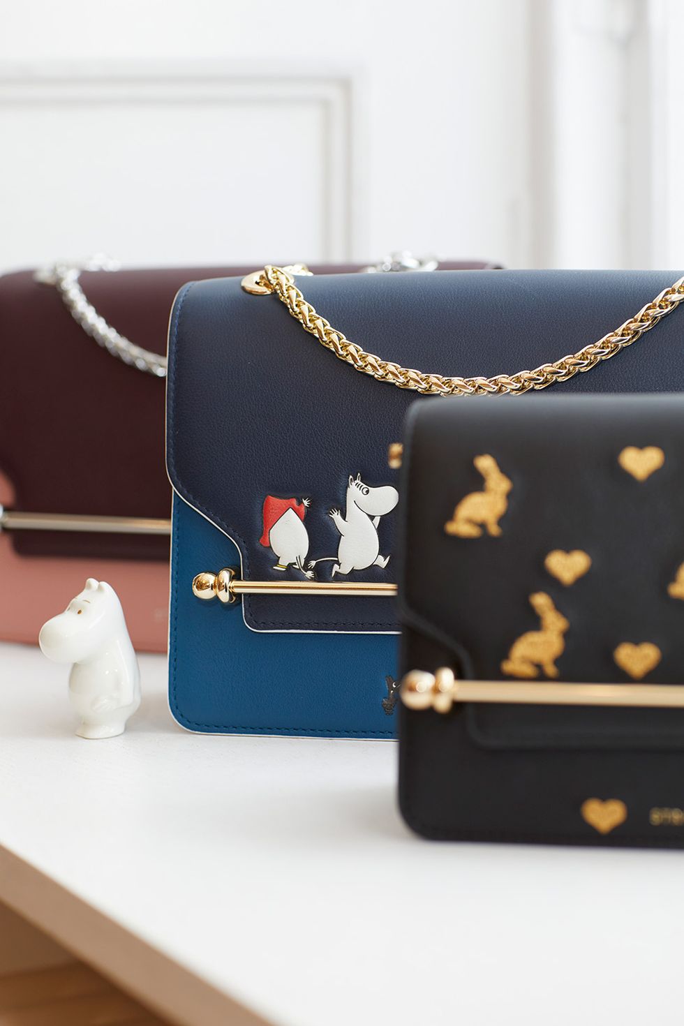 a black purse with gold and silver accents and a white hippo on the front