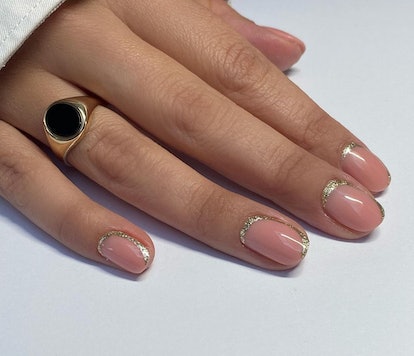 For a simple Christmas nail design for the 2023 holiday season, neutral nails with festive gold glit...