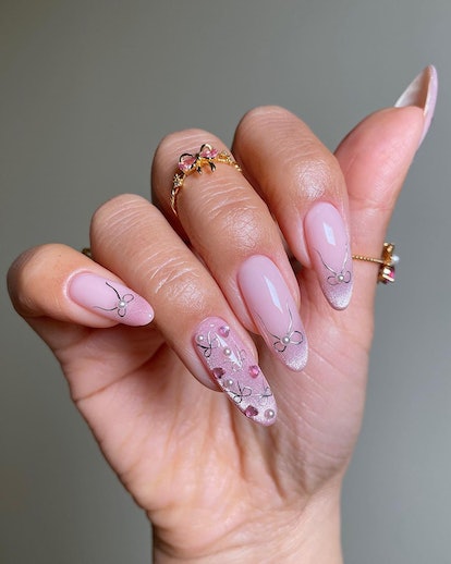 Sheer pink nails with silver coquette ribbon nail art is a simple manicure design idea for New Year'...