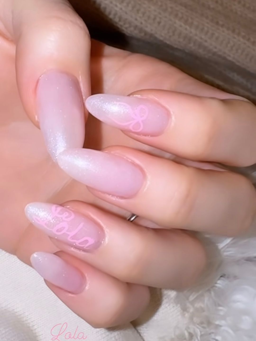 Nicola Peltz's pink shimmery nails with a bow on one finger and the word 