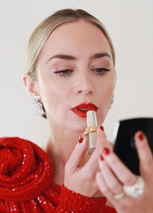 woman applying lipstick wearing red nail polish 