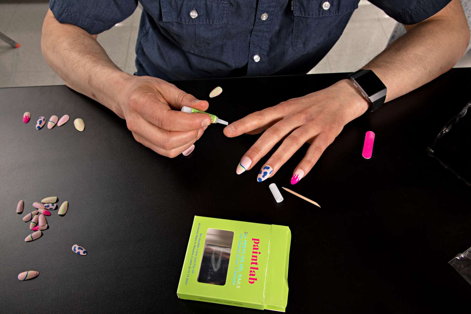 Person applying glue to a nail from the PaintLab Press-On Nails kit