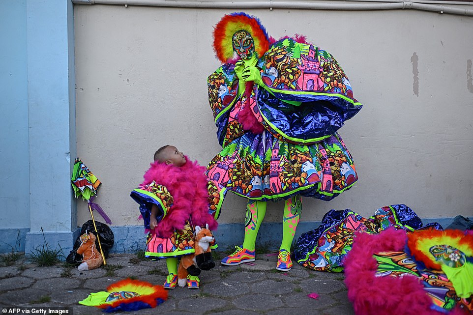 A member of the 'Bolo Doido' bate-bola street carnival group and his toddler get ready before a parade in a street at the Deodoro neighbourhood. Carnival is big business for Rio: the party is expected to generate 5.3billion reais (more than $1billion) in revenue this year