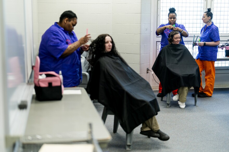 Michelle Lam, 38, hold an iron, right, as Evon Edmonds-Childs, 27, styles Amanda Tufts’, 36, hair during a barber and beauty school class on Tuesday, March 12, 2024, at St Louis County Justice Services in Clayton. The students will be graduating from the program in the next few weeks.