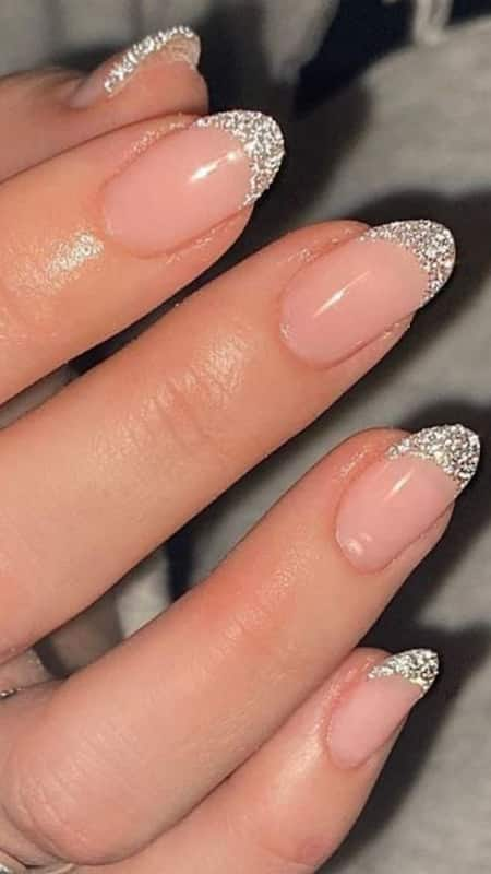 Glittering Glamour: Short, neatly manicured nails with a pink base and sparkling silver glitter on the tips, adding a touch of celebration.