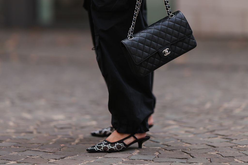 Julia Zwingenberg wearing Balenciaga black logo cap, striped black and beige Arket sweater, Chanel medium black leather flap bag, Preach wide leg pants and Gucci sparkling shiny logo print heels 