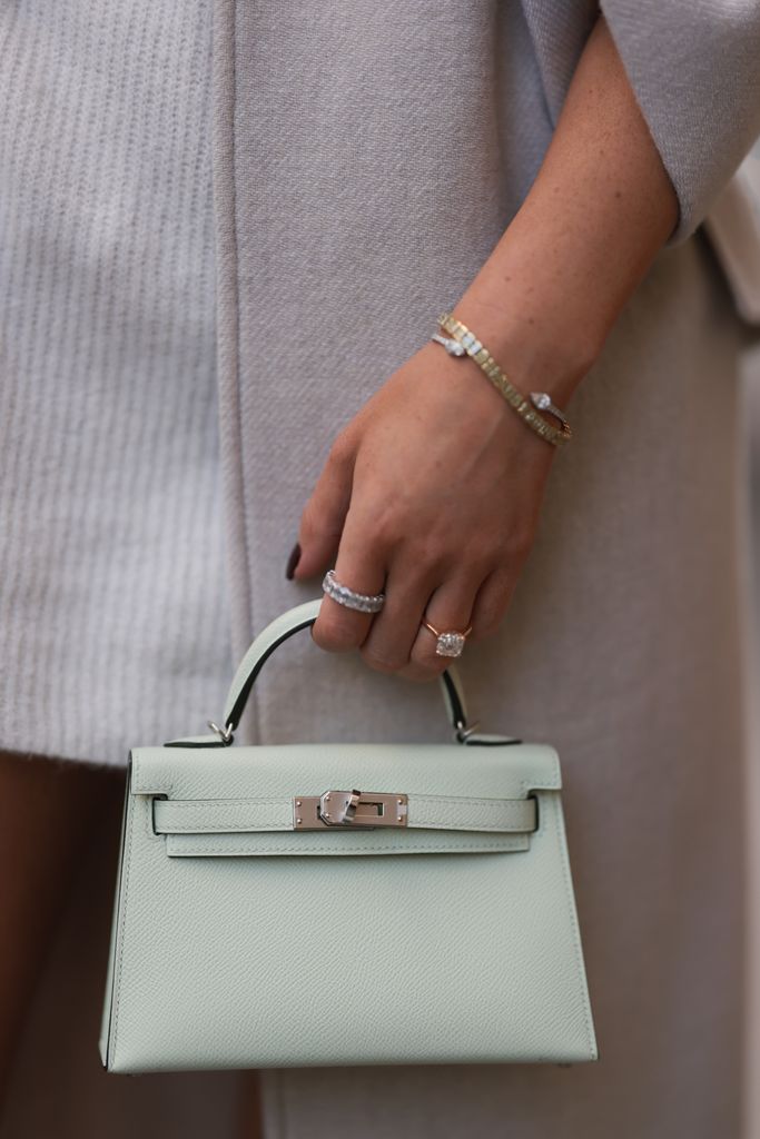 Leo Eberlin wearing Zara beige coat, H&M beige knit sweater dress, Hermes light green mini leather Kelly bag, Rolex gold Oyster Daydate watch and Leo Mathild jewelry on October 28, 2022 in Berlin, Germany. 