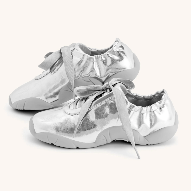 A pair of silver sneakers with soft fabric-like uppers, thick ribbon-like shoelaces, and chunky soles