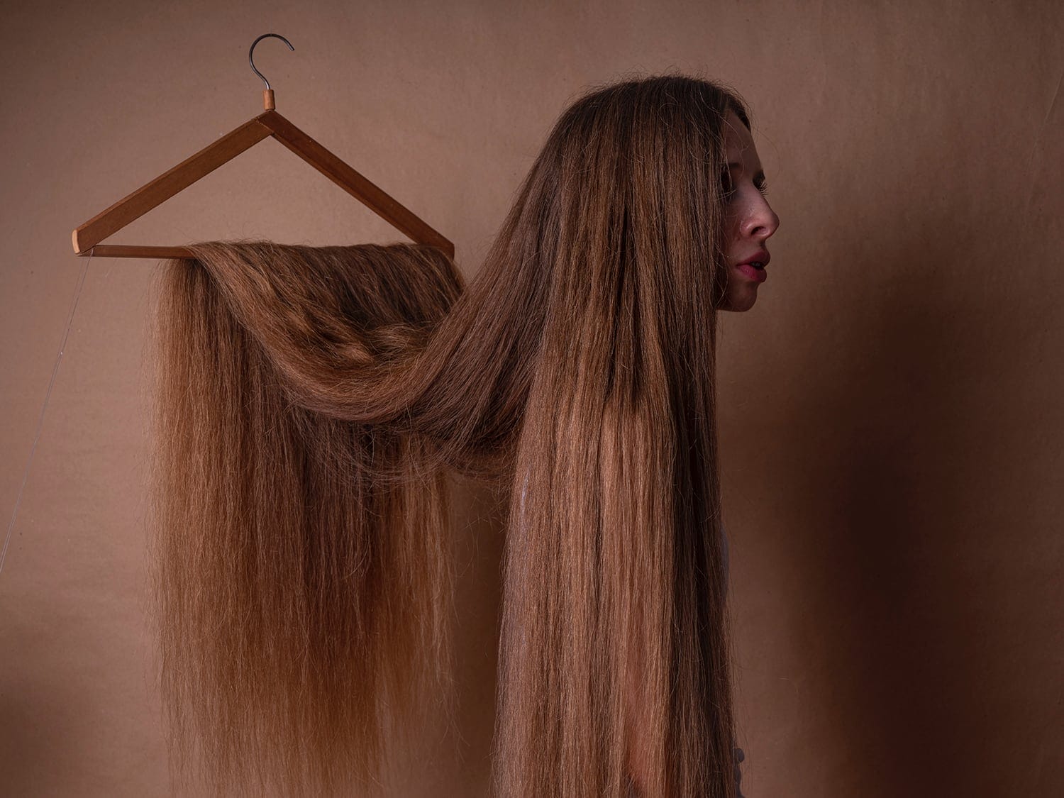 a woman masked by her hair, which hangs from a hanger and camouflages her entire body