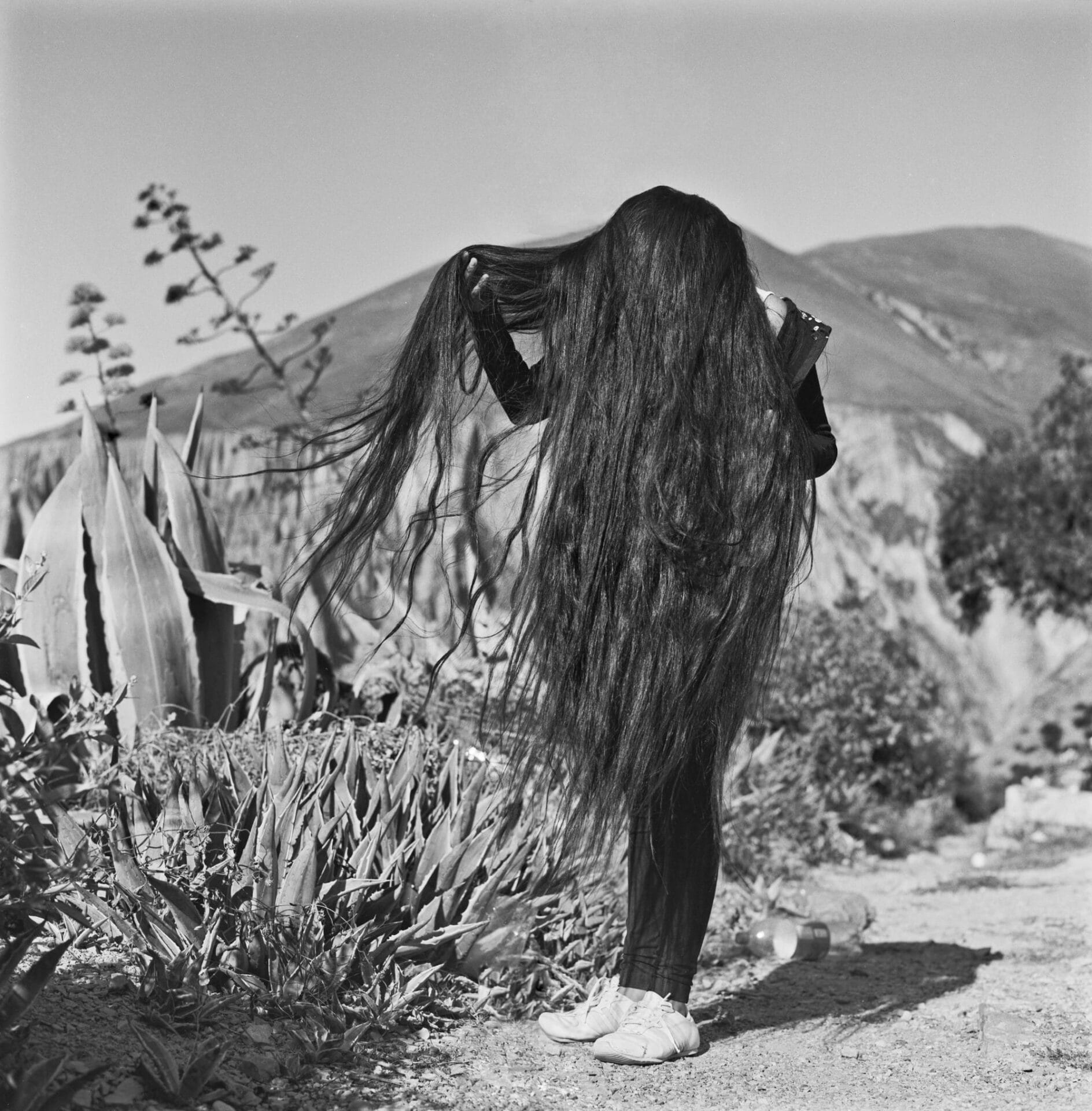 a black and white photo of a young girl whose hair goes to her knees and covers her face