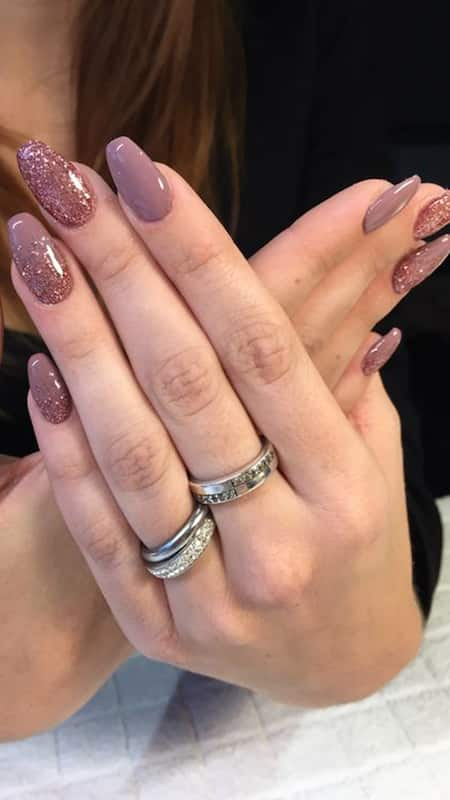 Almond-shaped nails in a muted mauve, half adorned with a sparkling glitter overlay, creating a glamorous yet sophisticated look