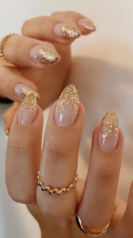 Soft pink nails boasting a luxurious cascade of gold glitter, exuding opulence and a flair for the dramatic.