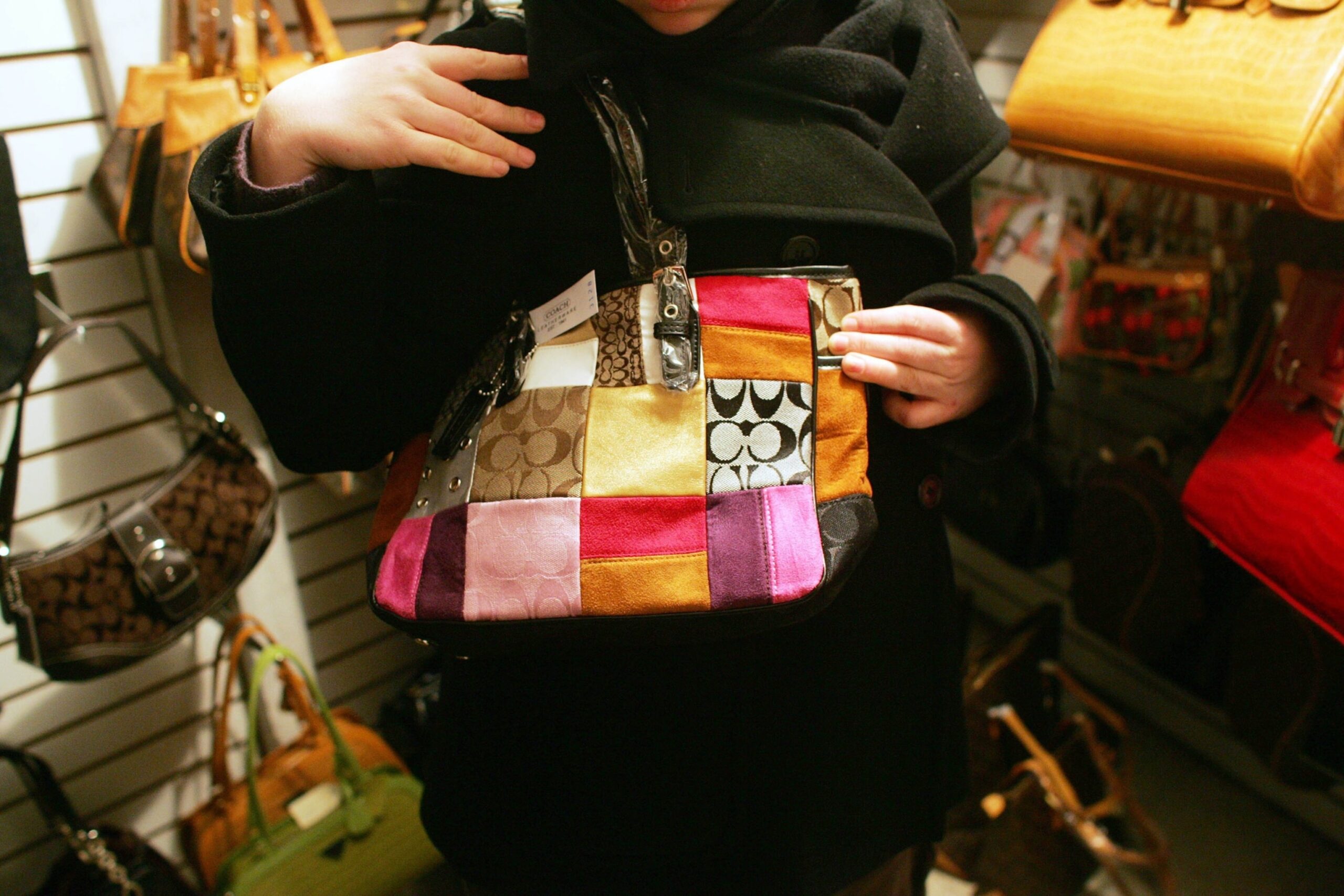 PHOTO: In this Feb. 1, 2006, file photo, an unidentified woman holds up a counterfeit Coach handbag in the back room of tourist shop in New York's Chinatown.