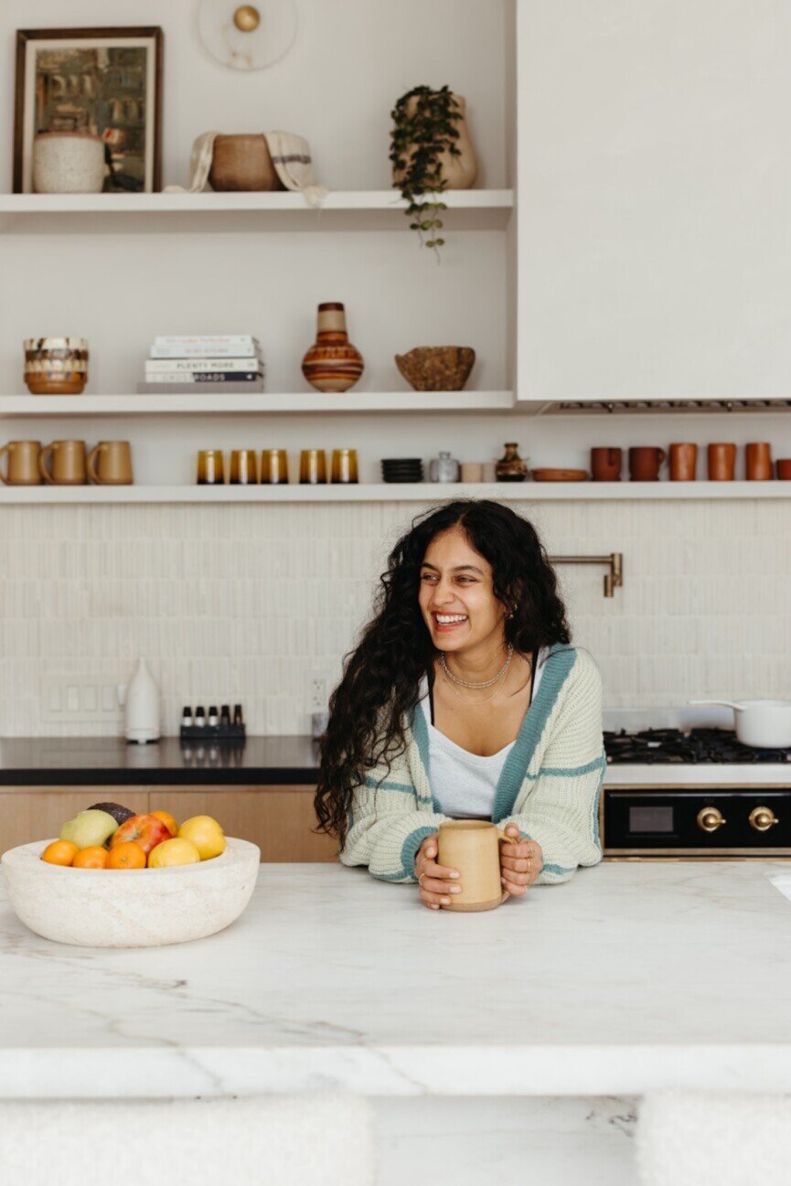 Woman holding mug in kitchen.