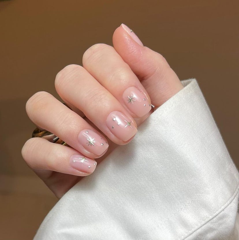 Neutral nails with silver celestial star details are perfect for Cancer season 2024.