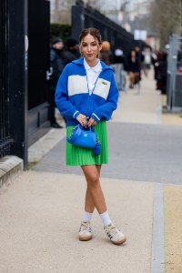 PARIS, FRANCE - MARCH 05: A guest wears blue white zipper jacket, green pleated skirt, bag outside Lacoste during the Womenswear Fall/Winter 2024/2025 as part of  Paris Fashion Week on March 05, 2024 in Paris, France. (Photo by Christian Vierig/Getty Images)