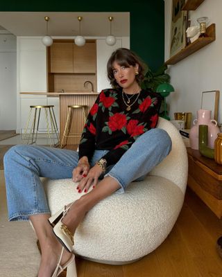 @juliesfi sitting on a chair wearing bright red nail polish