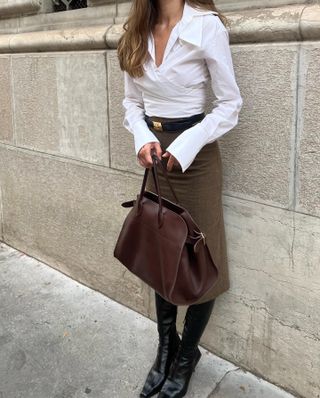 a woman carries The Row's Margaux bag in brown