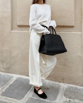 a woman carries The Row's Margaux bag in black