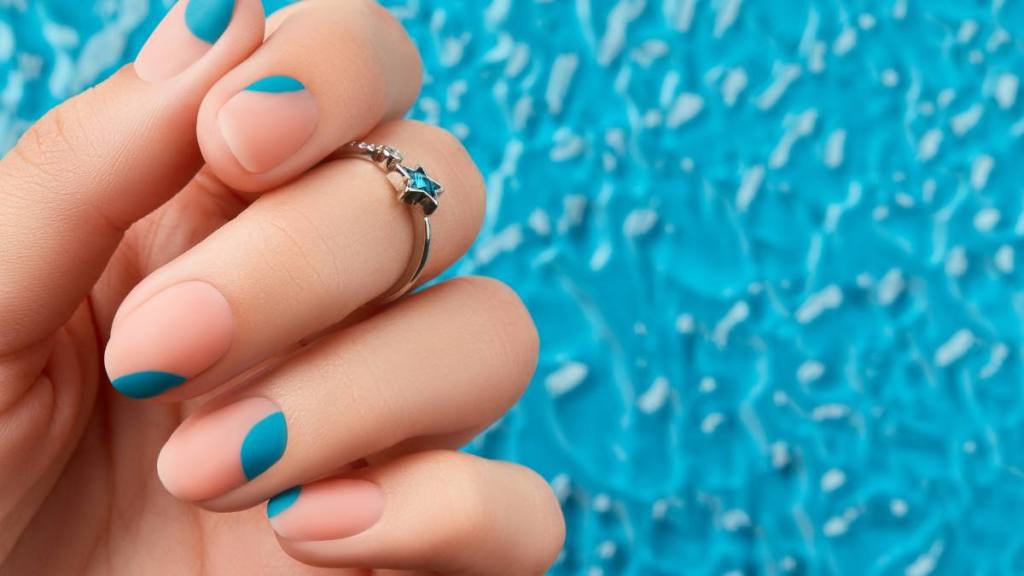 Close up womans hand with summer manicure on blue background. Manicure design trends. Beauty treatment concept (summer nail designs)