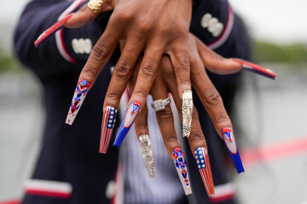 Sha'Carri Richardson, of the United States, shows off her nails while traveling along the Seine River, during the opening ceremony of the 2024 Summer Olympics