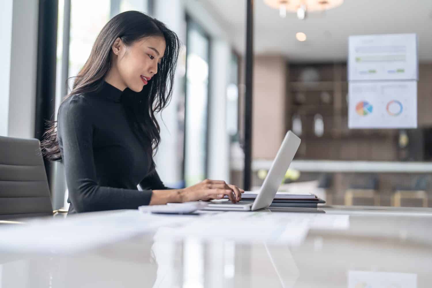 Beautiful confident asian business woman working with laptop Hands typing keyboard. Professional investor working new start up project. business planning in office. Technology business.