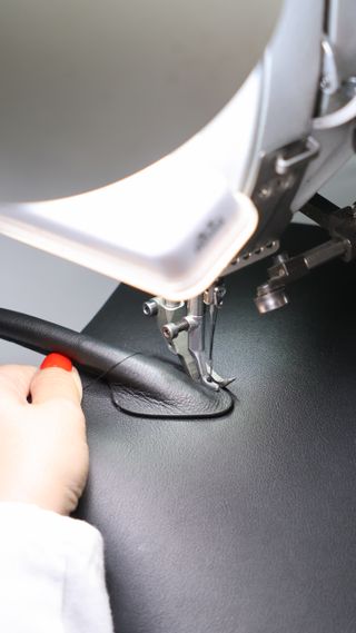 an artisan sews the handle on to a strathberry bag in the ubrique spain factory