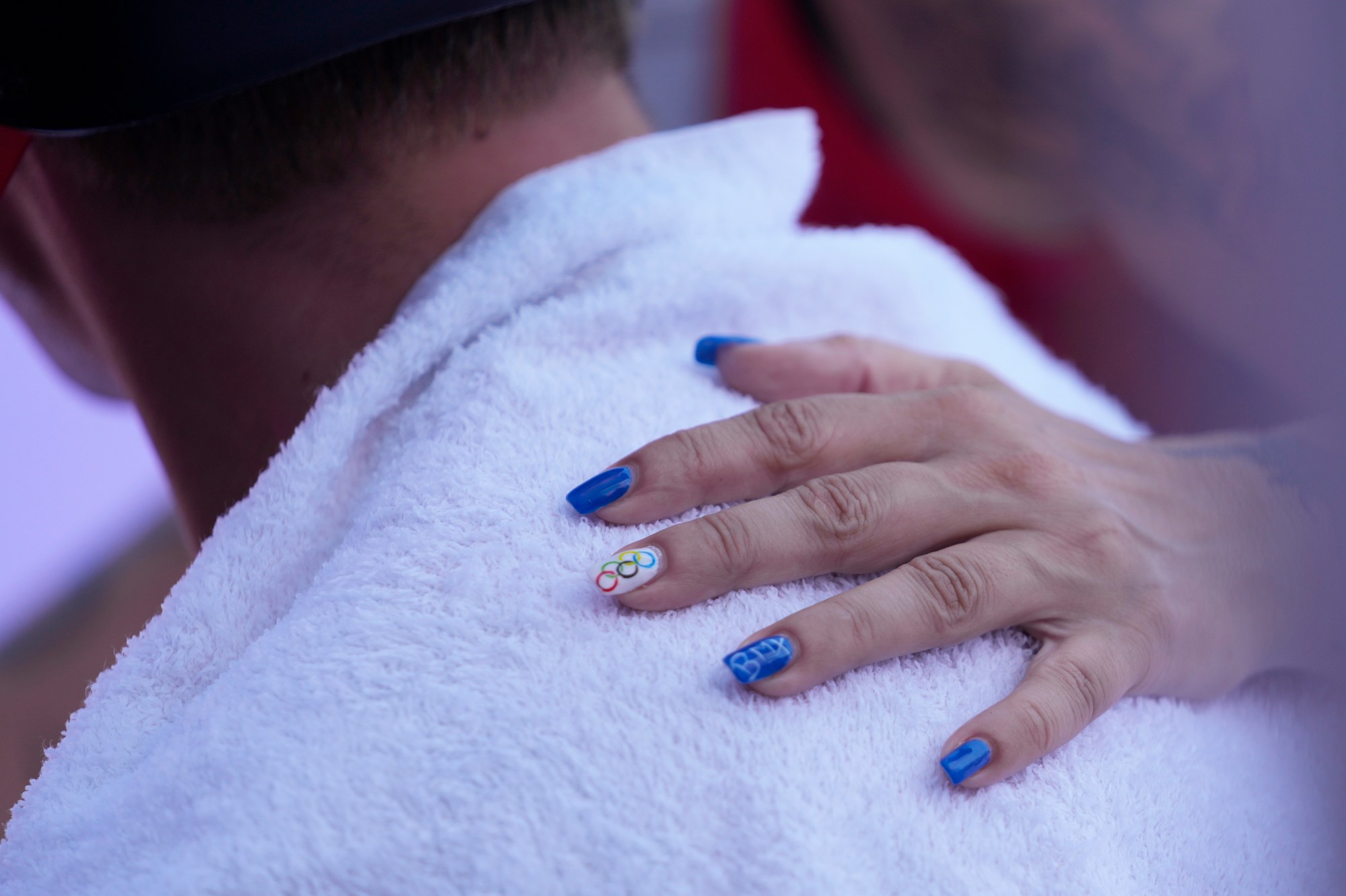 Croatia team leader Sunsica Cebecic, her nails painted for the occasion, pats Marin Rantes, of Croatia, during the cycling BMX freestyle men's park qualification at the 2024 Summer Olympics, Tuesday, July 30, 2024, in Paris, France. Rantes failed to qualify for the final. (AP Photo/Frank Franklin II)