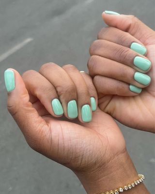 A woman's hands with a turquoise manicure.